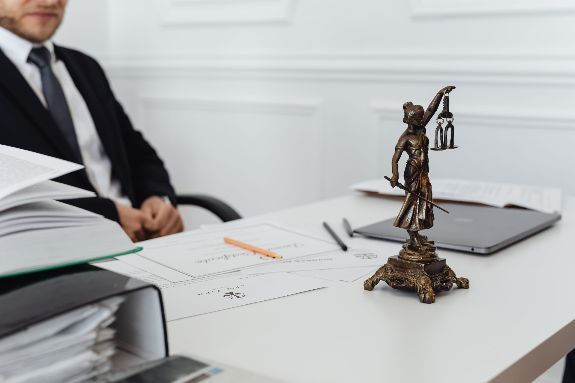 Solicitor at a desk with contract paperwork and a bronze statue of Lady Justice