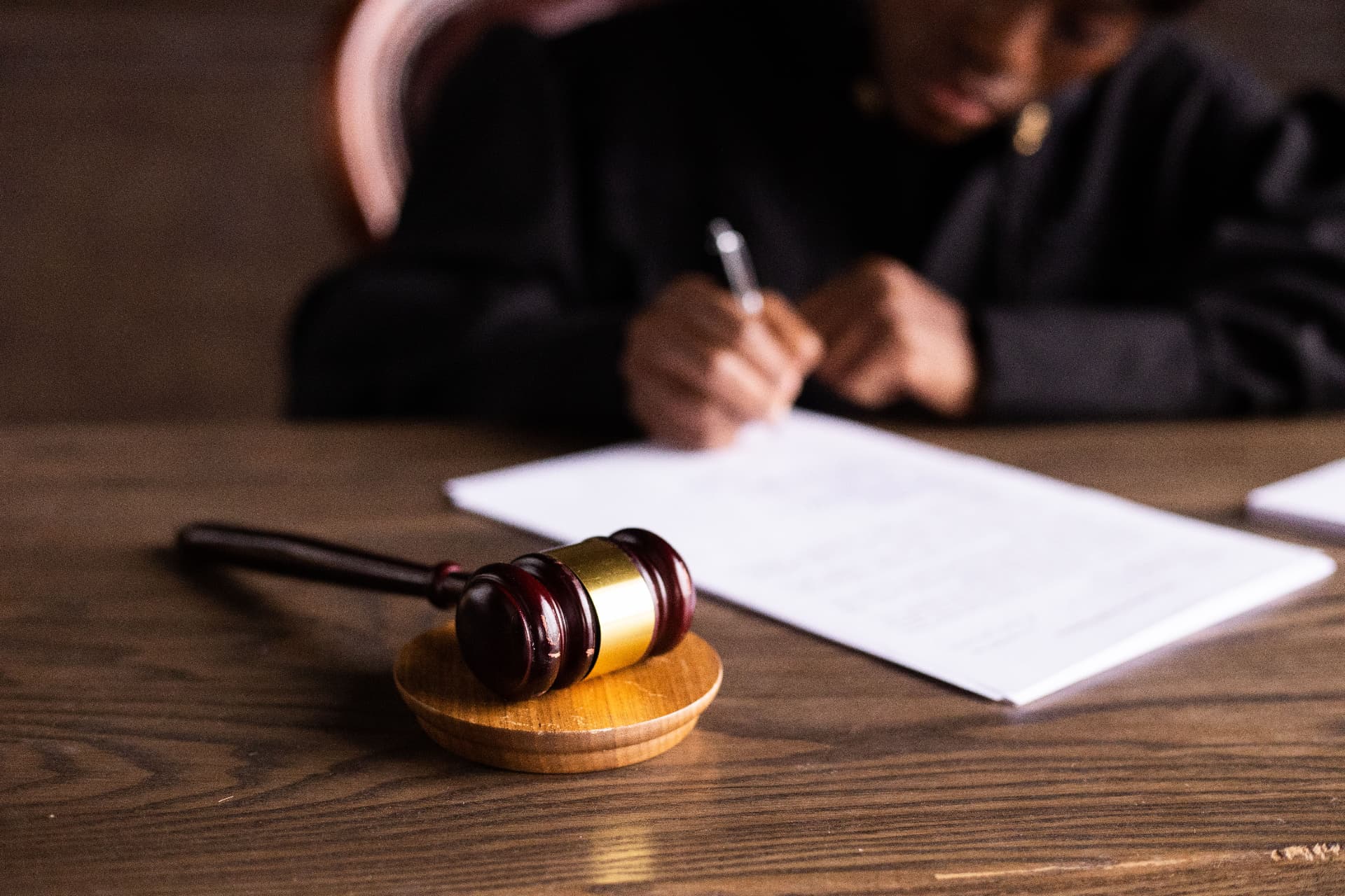 Wooden gavel resting on a desk while a judge signs a document