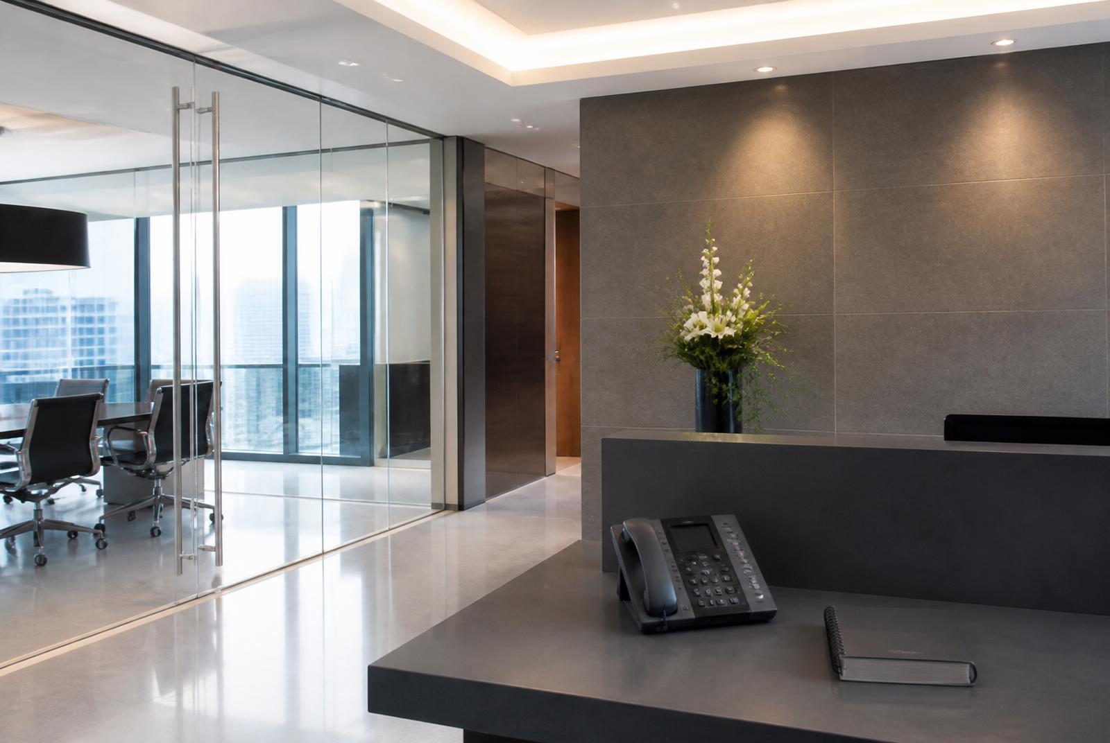 Modern corporate office reception with a glass-walled meeting room and a minimal desk